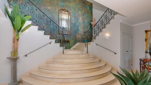Una amplia escalera con barandillas de metal ornamentadas y un espejo decorativo en la parte superior.