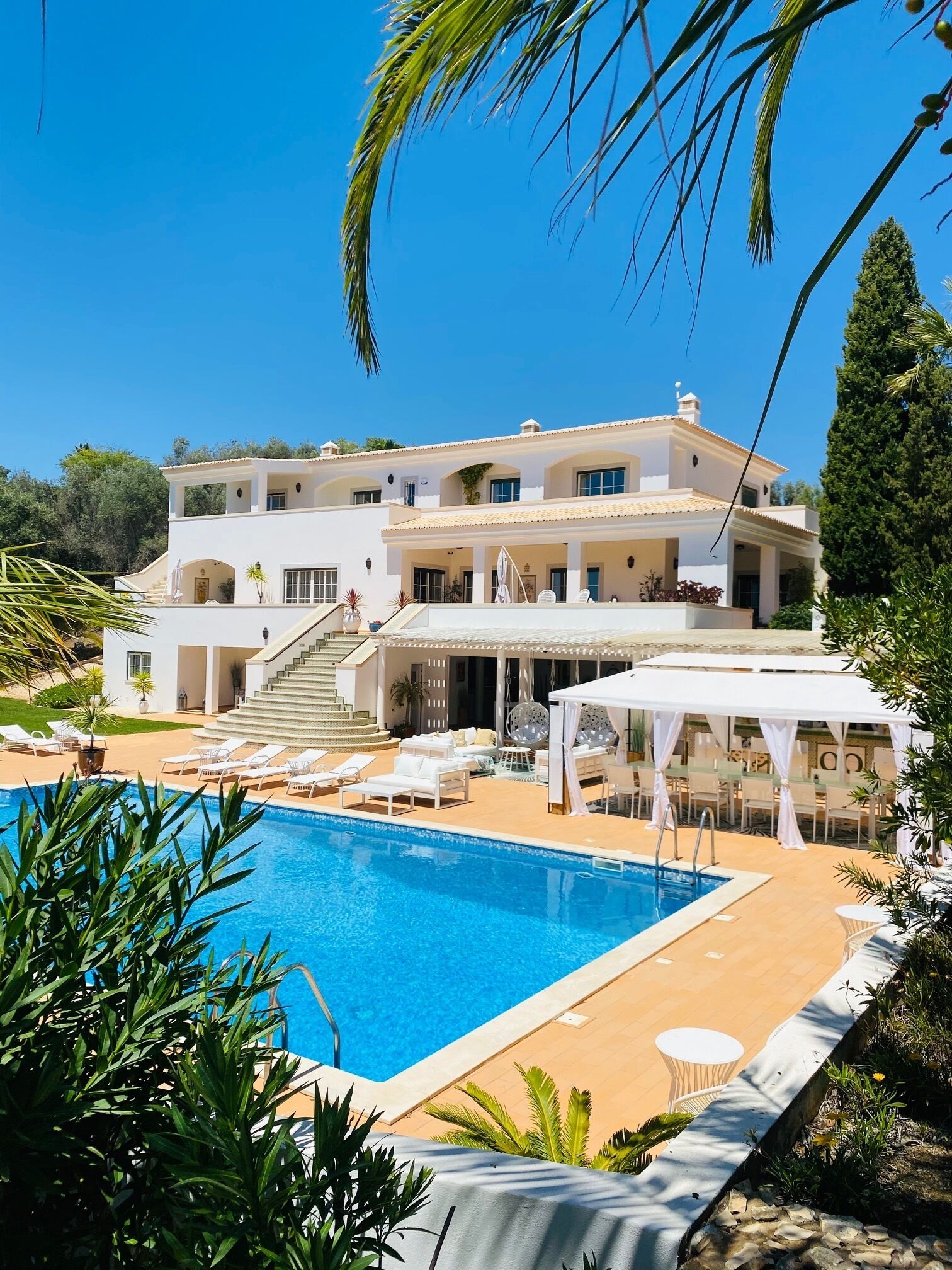 Ein zweistöckiges Gebäude mit Pool, Außenbereich und überdachter Terrasse.