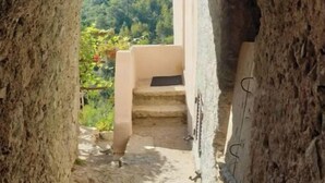 Ein Steinkorb führt zu einer Treppe mit Blick auf einen üppigen, grünen Hang.