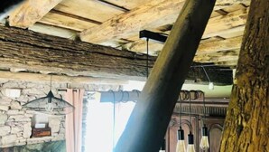 Ein rustikales Interieur mit sichtbaren Holzbalken, einer Steinwand und einem alten Holzschrank.