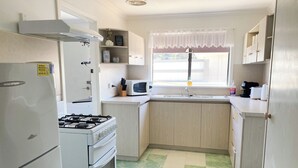 Eine kleine Küche mit Kühlschrank, Herd, Mikrowelle und Spüle.