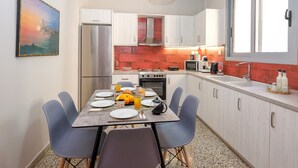 Una cocina moderna con una mesa de comedor para cuatro personas, un refrigerador, un microondas y una estufa.