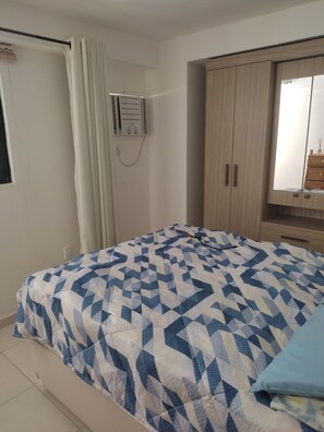 Quarto com cama, guarda-roupa e janela com cortinas.