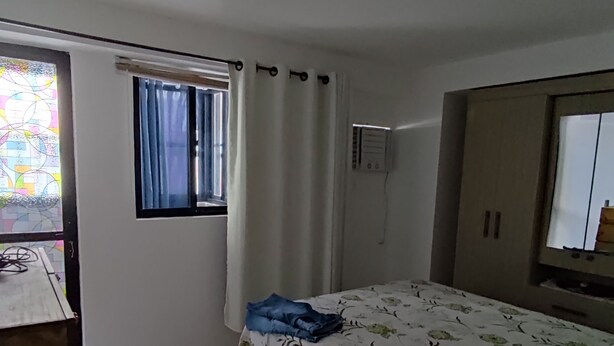 A bedroom with a bed, a window with curtains, a desk with a chair, and a wardrobe. - Praia de Manaíra (João Pessoa)