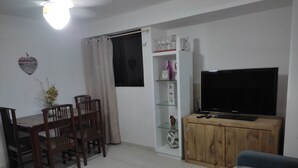 A living room with a TV, wooden cabinet, and a dining area with chairs and a table. - Praia de Manaíra (João Pessoa)