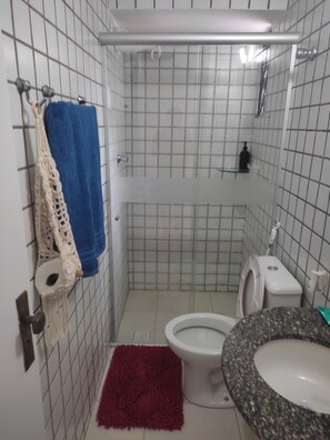 Casa de banho com chuveiro, sanita e lavatório.