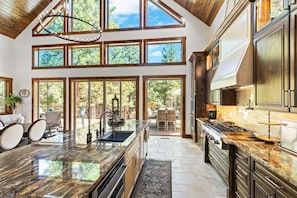 A spacious kitchen with a large island, multiple windows, and a view of the outdoors.