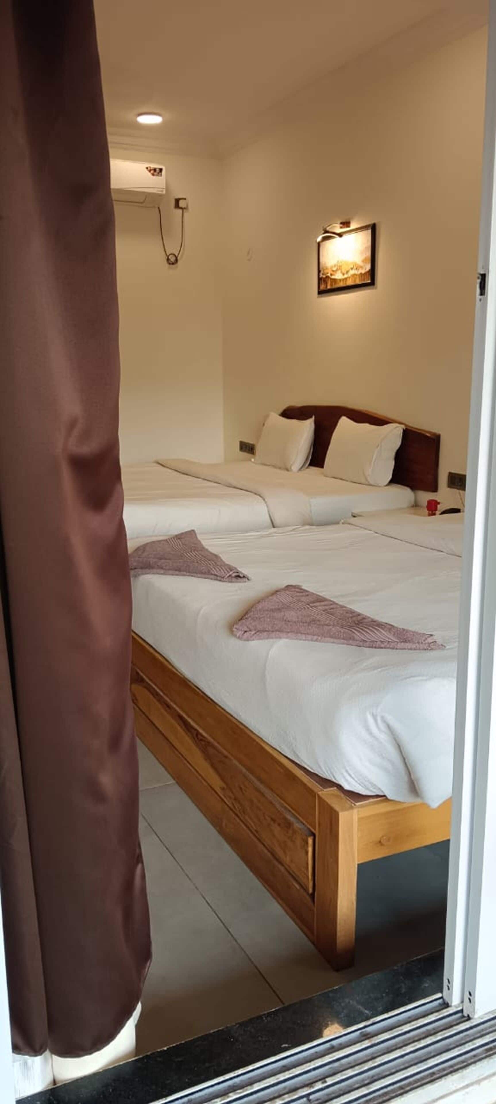 A bedroom with a wooden bed frame, white bedding, and a wall-mounted light fixture.