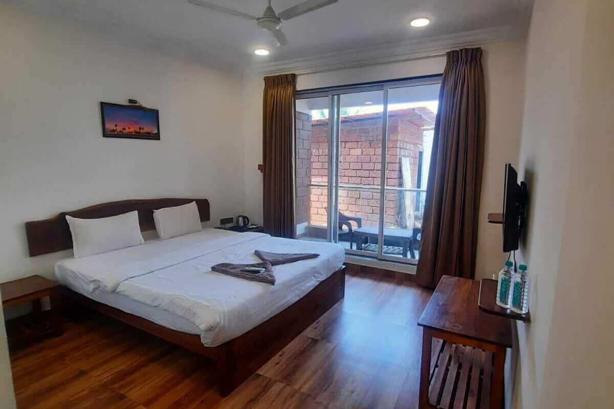 Hotelkamer met een groot bed, een plafondventilator, een televisie en uitzicht op buiten.