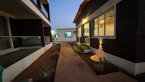 Une cour avec un chemin, des plantes en pot et un bâtiment doté de grandes fenêtres.