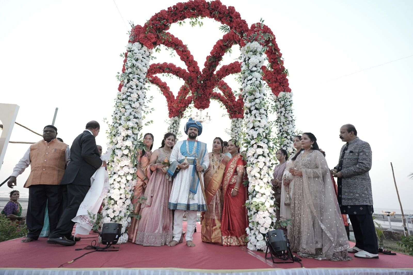 A group of people on a stage with a floral arch backdrop.