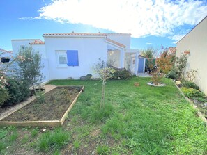 A residential property with a garden, a raised vegetable bed, and a small patio area.