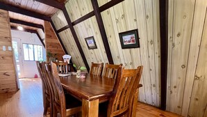 A wooden dining table with chairs in a room with wooden walls and a sloped ceiling.