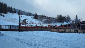 Et skisportssted med sne, træbygninger, en stenvæg og et træhegn.