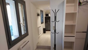 A hallway with a coat rack, a radiator, and a view into a kitchen area. - Large cozy studio in Castellane /Gorges du Verdon (Castellane)