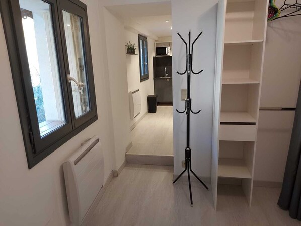 A hallway with a coat rack, a radiator, and a view into a kitchen area. - Spacious, cozy studio in Castellane / Gorges du Verdon (Castellane)