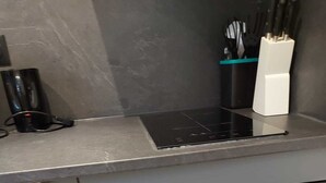 A compact kitchen with a built-in oven and dishwasher, a black countertop, and a knife holder. - Large cozy studio in Castellane /Gorges du Verdon (Castellane)