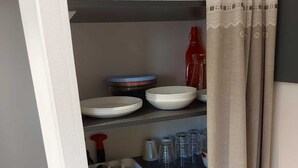 A kitchen with shelves holding plates, bowls, cups, and a kettle. - Large cozy studio in Castellane /Gorges du Verdon (Castellane)