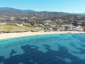 A coastal town with a beach, a marina, and buildings in the background.
