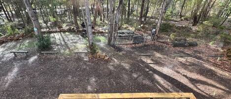 A forested area with picnic tables and a small seating area with a table and chairs.