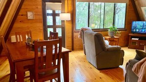 Een gezellig houten blokhut interieur met een eettafel, stoelen, een bank en een televisie.