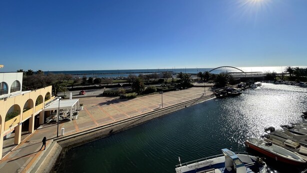 A waterfront view with a clear sky, a bridge, and boats docked.
