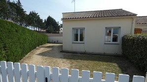 Una casa a due piani con tetto in tegole, giardino recintato e prato curato.
