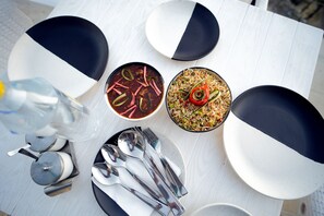 Pöytä on katettu, ja siellä on kaksi kulhoa ruokaa, pullo ja ruokailuvälineet.