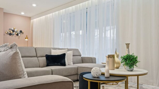 Een moderne woonkamer met een hoekbank, een ronde salontafel en decoratieve objecten.