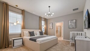 Een slaapkamer met een bed, nachtkastjes, een ledikant, een douche en een televisie.