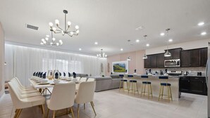 Een moderne keuken met donkere kastjes, een centraal eiland en barstoelen.