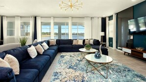 Una sala moderna con un sofá modular, una mesa de centro redonda y una televisión.