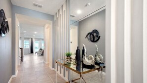 Un pasillo moderno con una pared divisoria de vidrio, superficie reflectante y objetos decorativos.