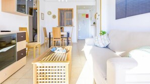 A modern living room with a sofa, a coffee table, and a dining area with chairs and a table. - Torremar by Interhome (Oropesa del Mar)