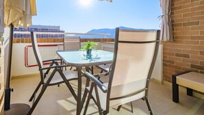 A balcony with a table and chairs, a potted plant, and a view of the sea and mountains. - Torremar by Interhome (Oropesa del Mar)