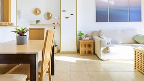 A modern living room with a dining area, a sofa, a coffee table, and a wall-mounted artwork. - Torremar by Interhome (Oropesa del Mar)