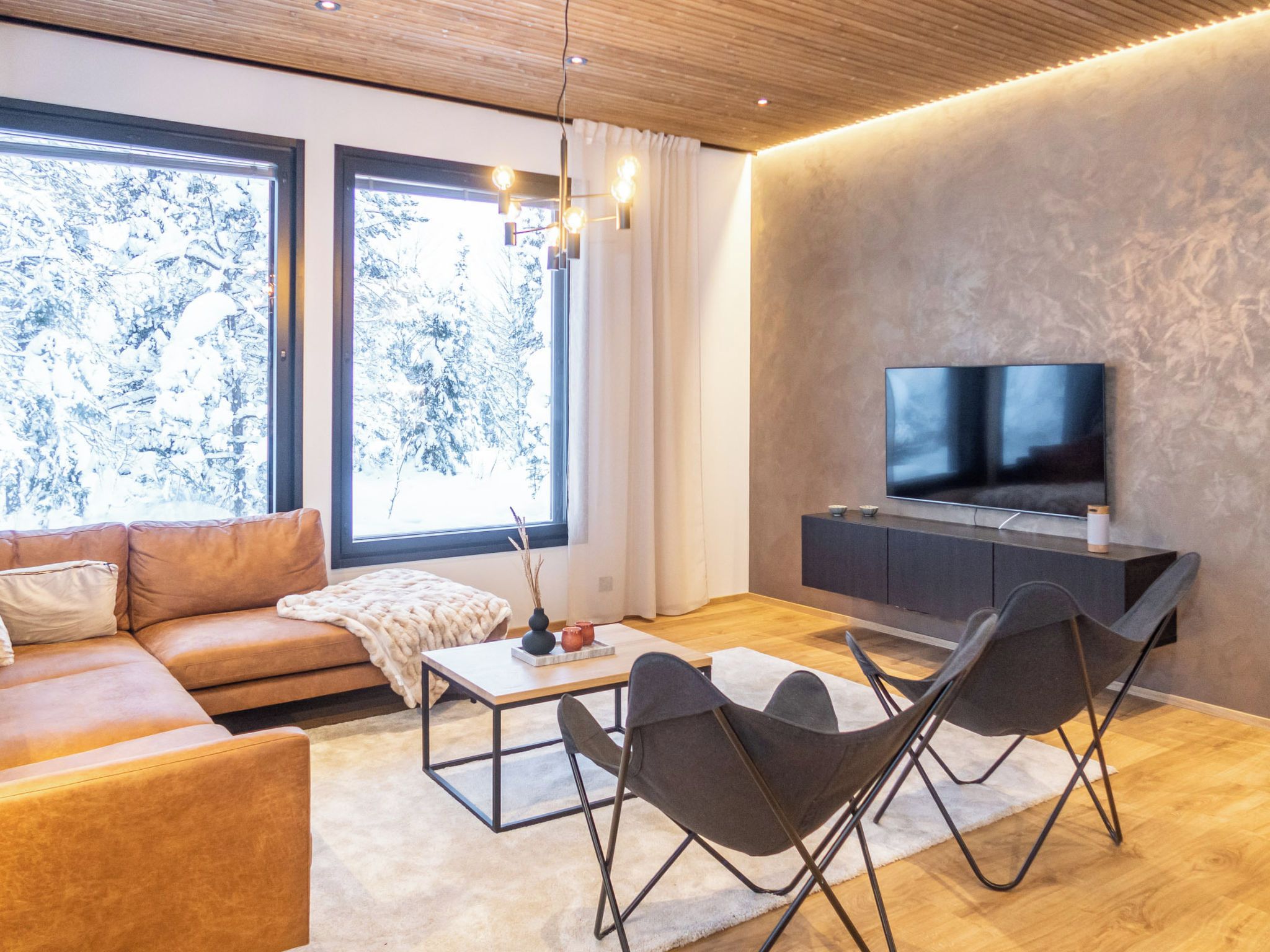 Ein modernes Wohnzimmer mit einer Couch, einem Couchtisch und einem Fernseher auf einem Schrank.