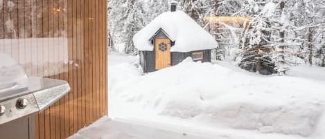 Una cabana de fusta amb un teulat cobert de neu, envoltada d'arbres carregats de neu.