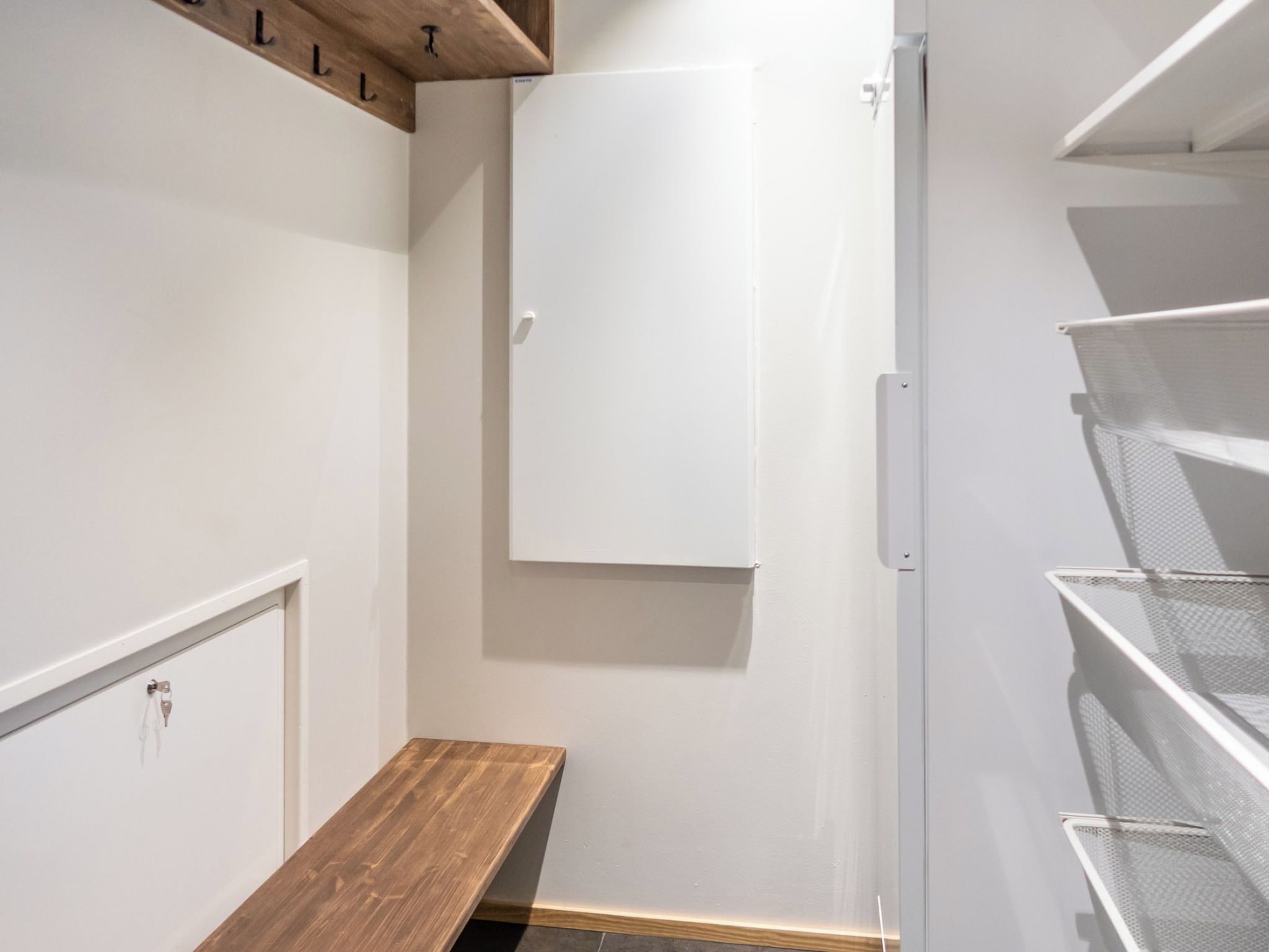 A storage closet with shelves, a wooden bench, and a white cabinet.