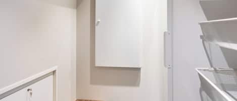 A storage closet with shelves, a wooden bench, and a white cabinet.