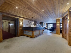 A reception area with a wooden ceiling, a reception desk, and a seating area with a chair.