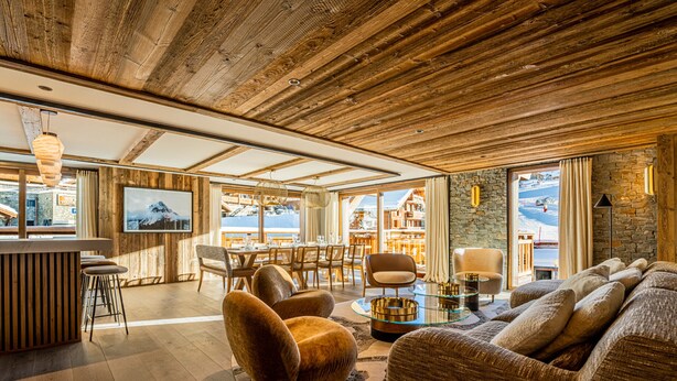 Un vaste espace de vie doté d’un plancher en bois, d’un grand canapé, d’une table à manger avec des chaises et d’un coin bar.