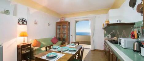 Un comedor con una mesa de madera dispuesta para cuatro personas, un aparador con puertas de vidrio y vistas al exterior a través de un vano.