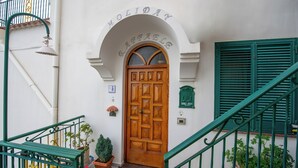 A wooden door with a white arch above it, a green staircase, and potted plants around the entrance. - Raphael House, terrace with solarium and sea view (Conca dei Marini)