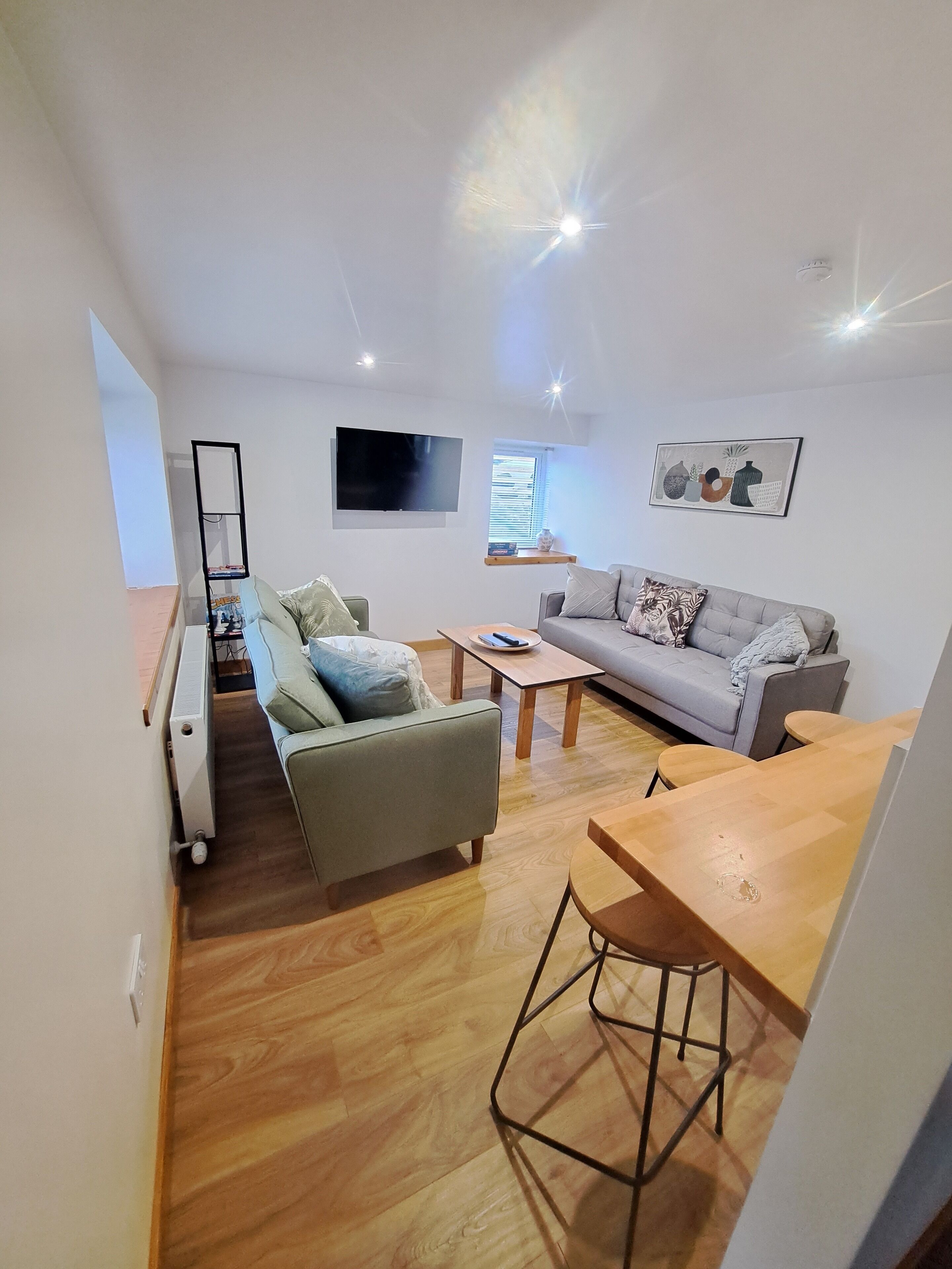 Un salon moderne avec un canapé, une table à manger et un téléviseur fixé au mur.