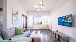 A modern living room with a sofa, coffee table, and a TV mounted on the wall. - Sunset View Apartment (Chania)