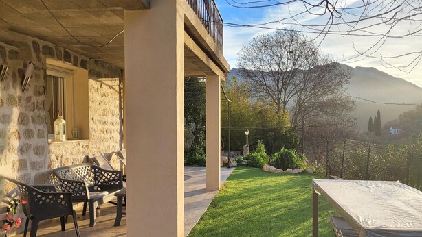 Une terrasse avec mobilier d’extérieur, un espace abrité et une vue sur un paysage montagneux.