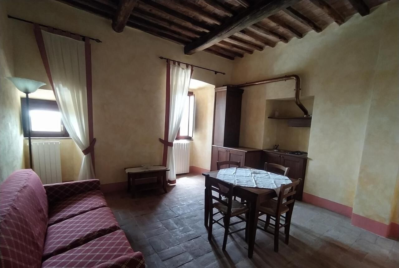 Una habitación acogedora con techo de madera, una mesa de comedor con sillas, un sofá y una ventana con cortinas.