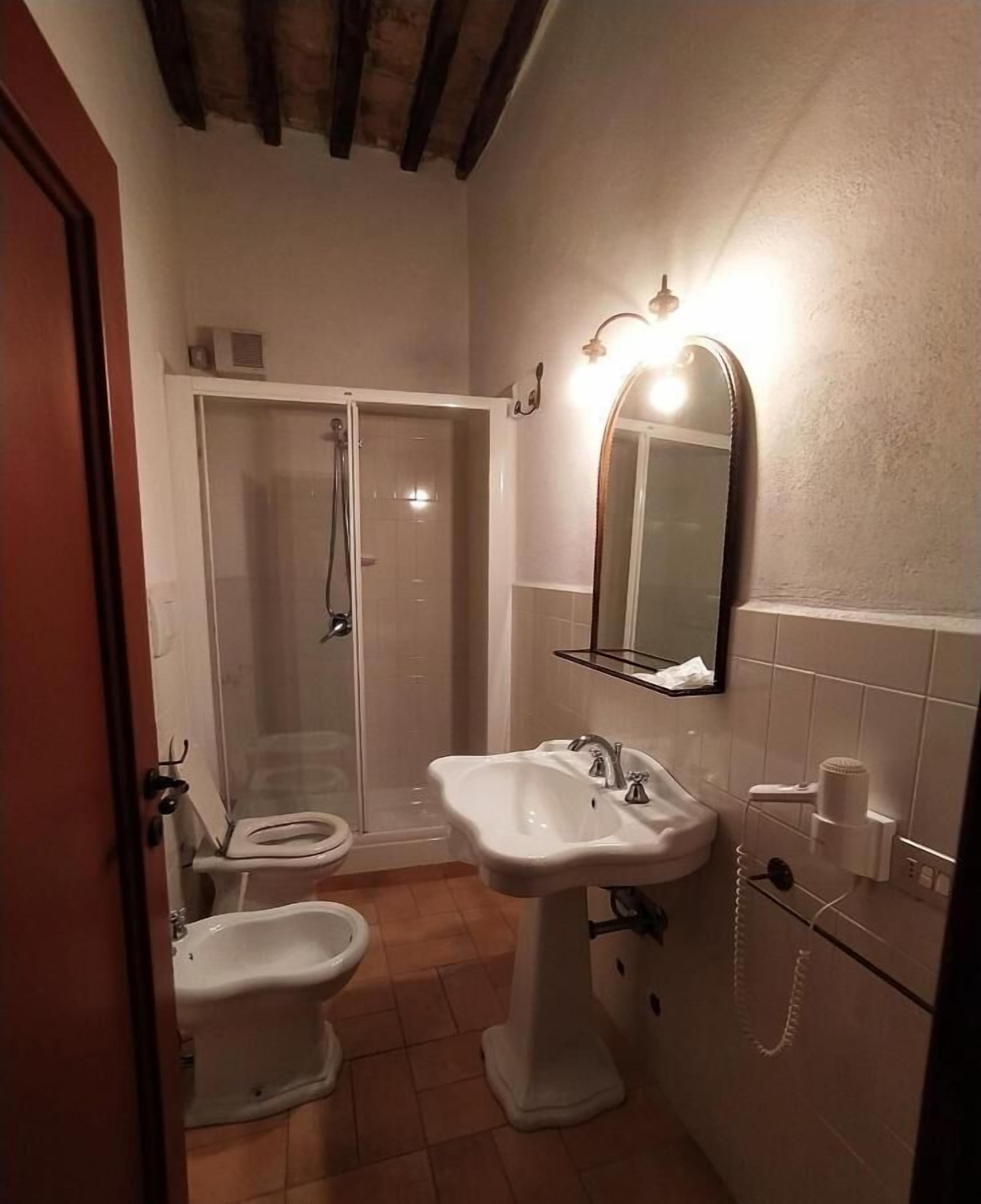 Casa de banho com chuveiro, sanita, bidé e lavatório.