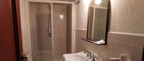 A bathroom with a shower, toilet, bidet, and sink.